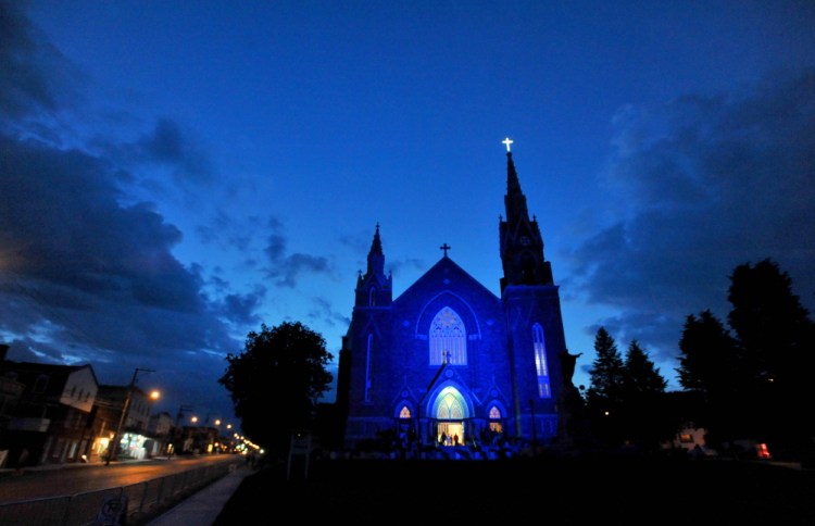 Ste-Agnes Catholic Church lights up in blue in the early hours of the morning during a vigil in Lac-Megantic, Quebec, on Sunday, July 6, 2014.