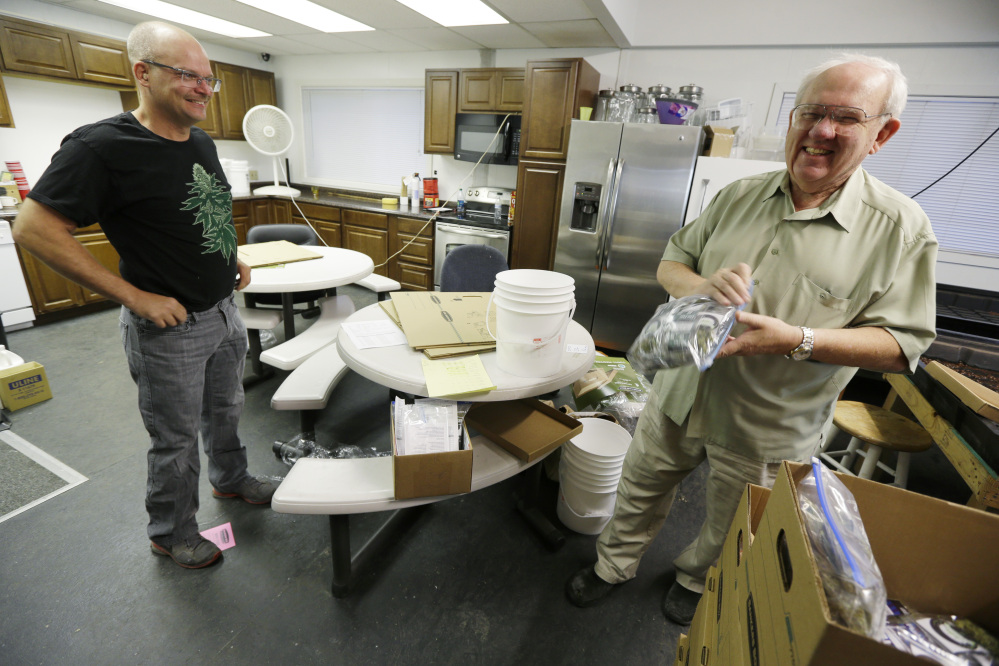 Bob Leeds, owner of Sea of Green Farms, right, has a laugh with farm director Phil Tobias, as they load packets of recreational marijuana into boxes, Tuesday in Seattle, for delivery to a store in Bellingham, Wash.