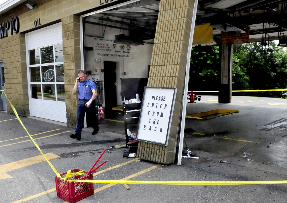 George Spencer, manager of the Prompto Oil franchise in Waterville, speaks on a phone Tuesday beside a damaged wall after a vehicle plowed into it earlier. Spencer said he had to move out of the way of the vehicle, which almost hit himt.