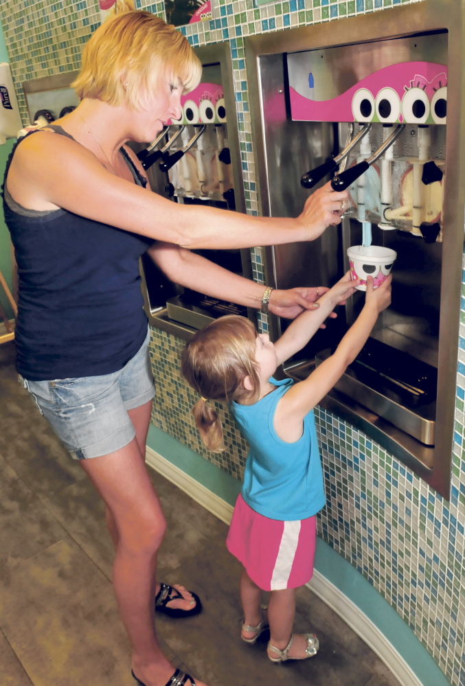 Jeanne Garza helps her daughter Rosabella pour her choice of frozen yogurt Wednesday at the new sweetFrog store in Waterville.