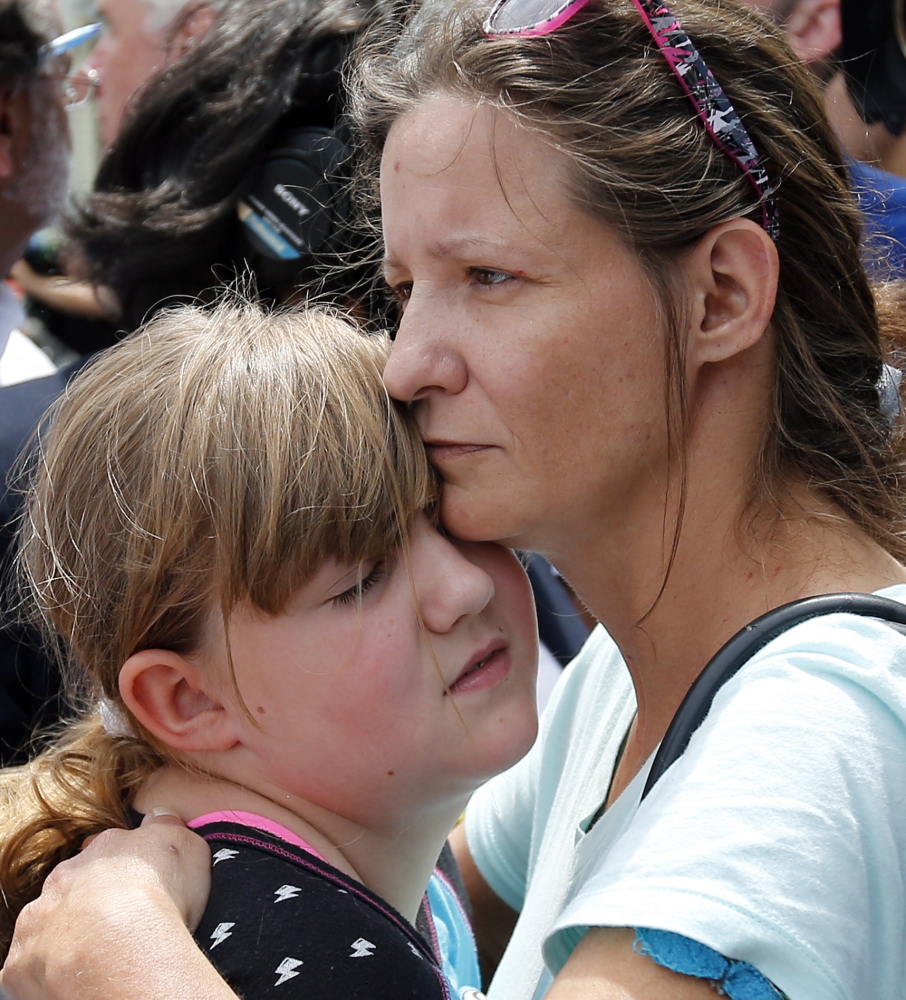 Geri Boyles of Lowell, Mass., hugs her daughter, Corinna, 10, outside a burned three-story apartment and business building in Lowell, Mass., on Thursday. The neighbors lost people they knew in the fast-moving pre-dawn fire where officials said seven people died.