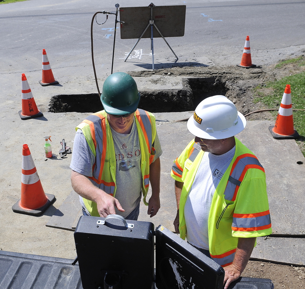 McGee Construction employees Tom Towns, left, and Ted Haskell record the pressure of a natural gas pipeline on Tuesday at the intersection of Maple and Greenville streets in Hallowell.