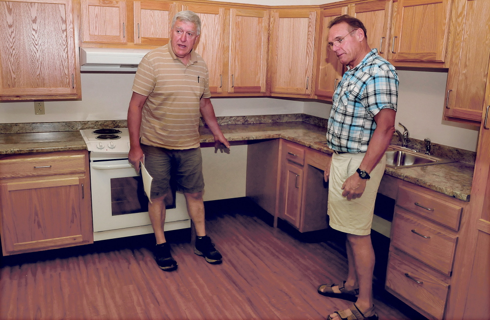 Byron Davis, left, and Bill Marceau, show one of the apartments in their newly opened Brookside Village senior residence in Farmington on Tuesday. Davis is explaining how counters are lower and allow access underneath for residents in wheelchairs.