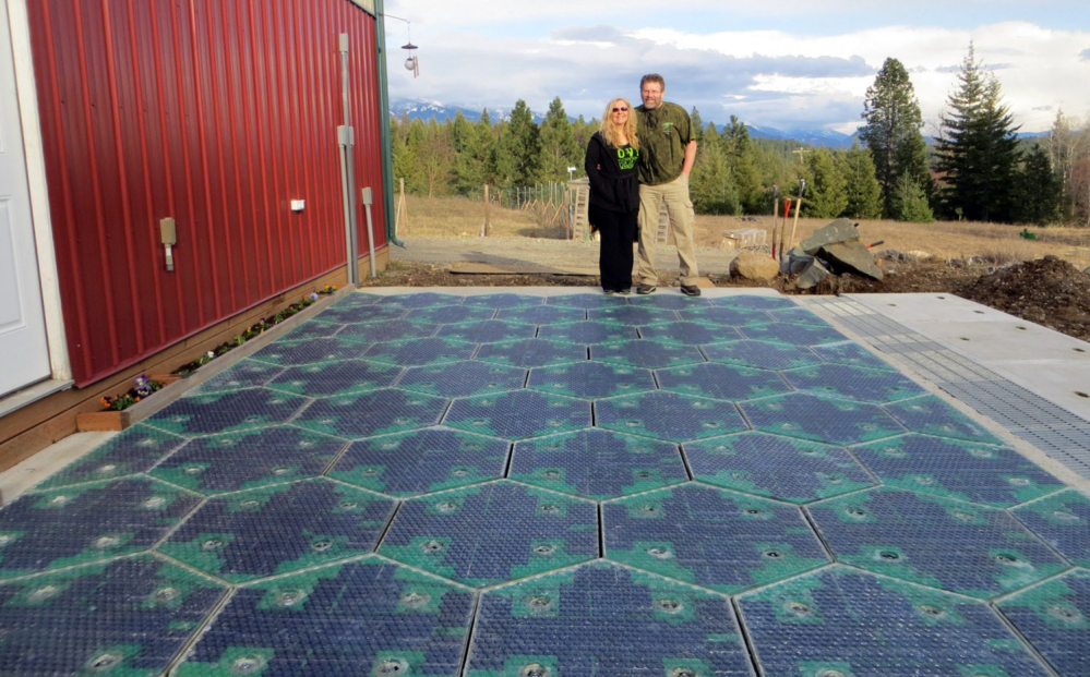 Scott and Julie Brusaw stand on a prototype solar-panel parking area at their company’s headquarters in Sandpoint, Idaho, in this photo provided by Solar Roadways.