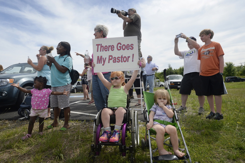 Four-year-old Sophia Emerson of Biddeford, accompanied by her 1-year-old sister Natalie, cheers   Members of The Rock Church in Scarborough cheer their pastor, Lt. Col. Eric Samuelson, as he made a final flight in the high-performance F-15, buzzing the Portland Jetport Thursday, July 10, 2014. Holding the sign in support of her pastor is Sophia Emerson 4, of Biddeford and to the right her younger sister Natalie Emerson, 1, of Biddeford. (Photo by Shawn Patrick Ouellette/Staff Photographer).