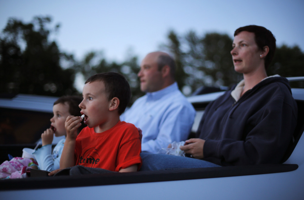 Mike and Naomi Gibel, and their children Norah, 4, left, and Issak, 7, watch a movie from the back of a pick-up truck at the Saco Drive-In in Saco.