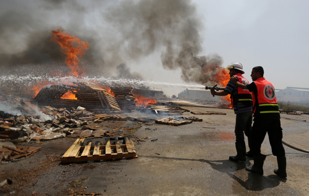 Palestinian firefighters try to extinguish a cargo terminal at Karni Crossing between Israel and Gaza  after it was shelled by Israeli tanks, according to terminal’s employees, on Saturday.