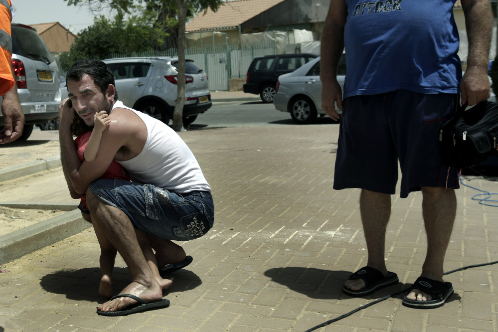 An Israeli hugs his child outside  a shelter as a siren warning of incoming rockets is heard around the southern city of Beersheba, Israel, Saturday.