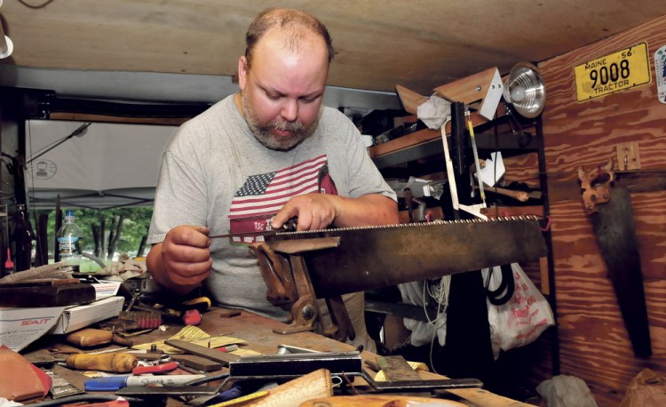 Vern Burke files the teeth on a hand saw Wednesday inside his mobile tool sharpening trailer parked at the Eddy in Skowhegan on Wednesday, July 9, 2014.