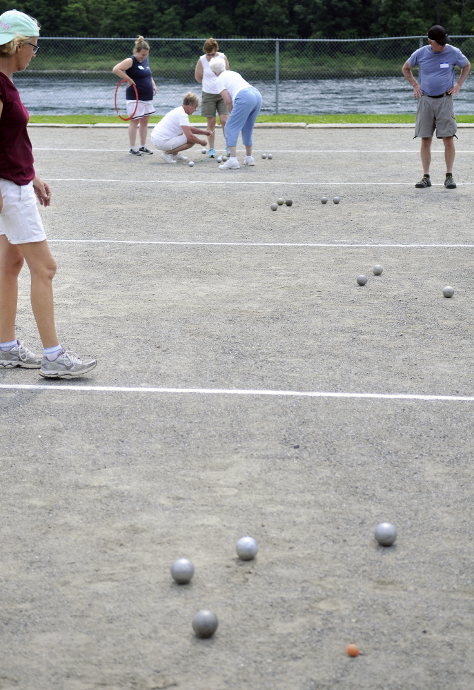 Petanque players assess their balls Sunday during a tournament at Mill Park in Augusta.