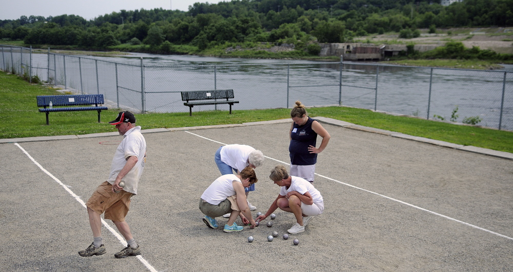 Mark Kindschi reacts Sunday to a bowl during the petanque tournament at Mill Park in Augusta as another team counts points at the court beside the Kennebec River.