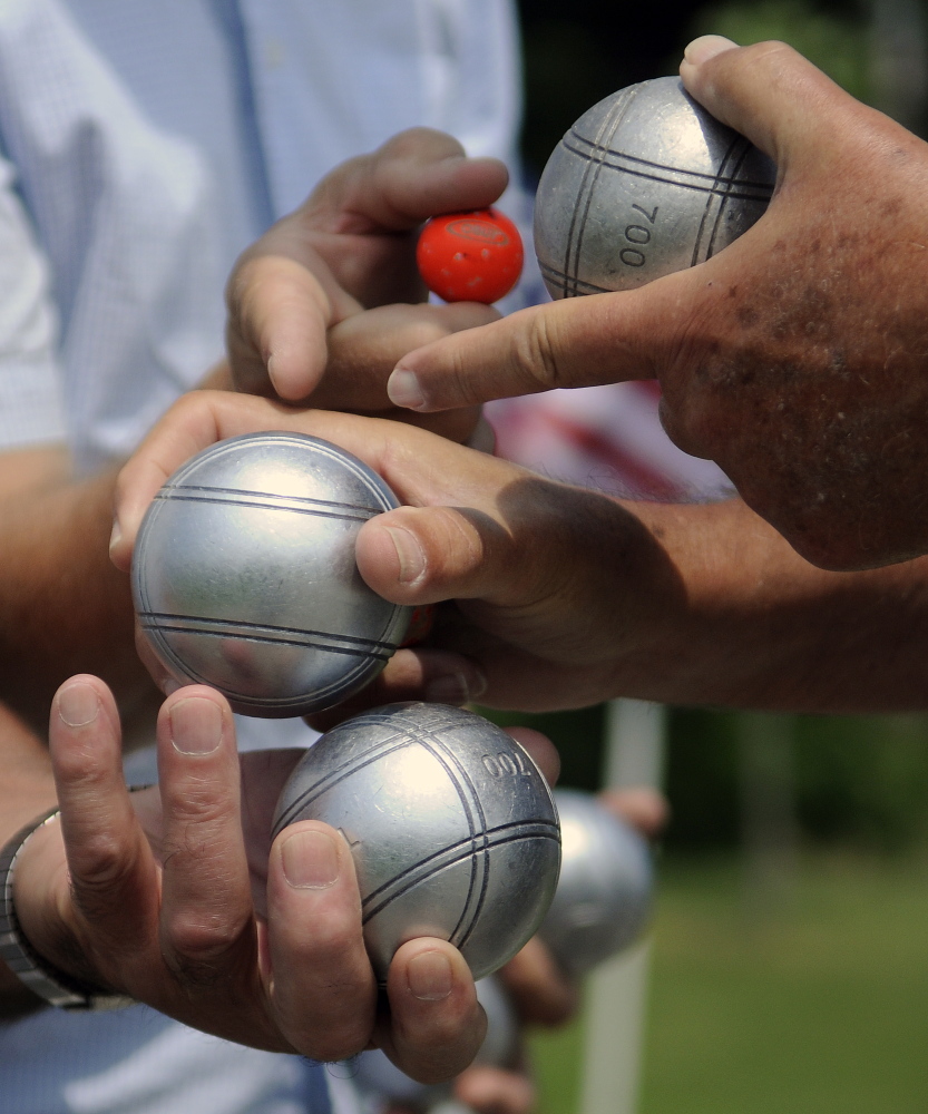 Petanque players note the differences among their balls Sunday before pitching a tournament match at Mill Park in Augusta. Balls are marked to distinguish them from those of competitors.