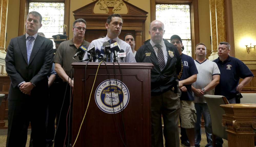 Jersey City Mayor Steven Fulop, center, addresses the media during a news conference talking about an early morning shooting which lead to a suspect and a Jersey City Police Department officer killed, Sunday, in Jersey City, N.J.