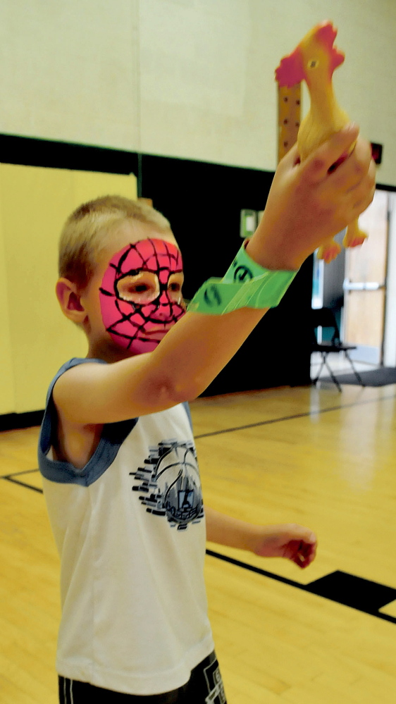 After getting his face painted Patrick Hyde takes aim with a rubber chicken before throwing it in distance competition during the Eggolympics held at the Warsaw School in Pittsfield on Wednesday. More events occur daily with a big parade scheduled for Saturday morning.