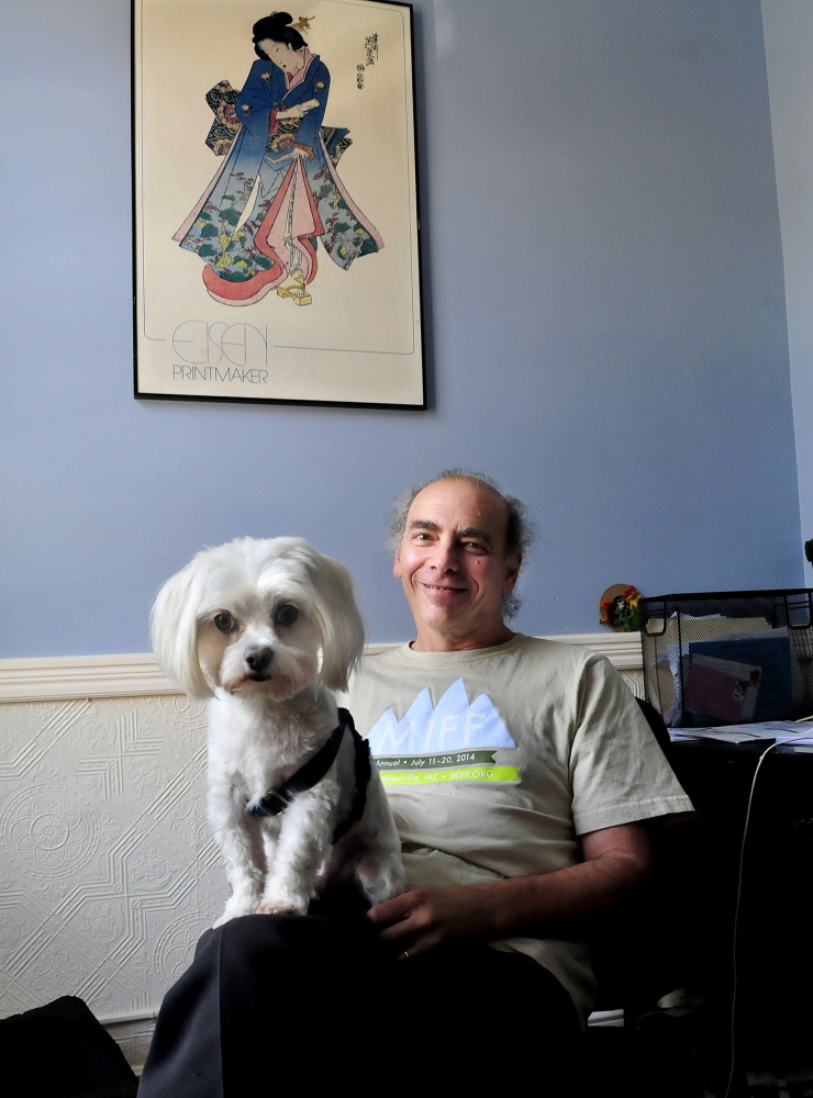 Ken Eisen, founder of Railroad Square Cinema and program director of the Maine International Film Festival, relaxes with his dog Puppers in an office in Waterville on Thursday. Eisen credits many people who contribute to the success of the cinema and MIFF while others say the credit rests with Eisen.