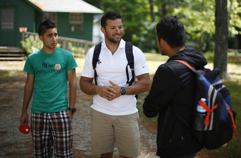 Seeds of Peace camp counselor Eias Khatib, 25, of Palestine, center, talks with a camper in Otisfield this week.