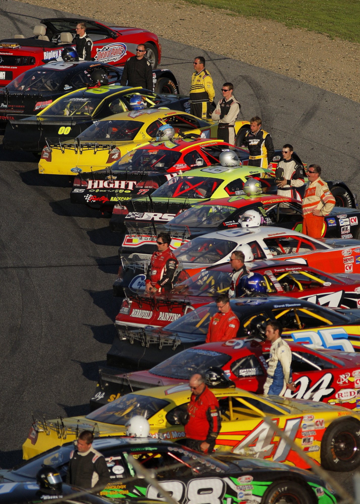 Drivers stand by their vehicles before the start of the National Anthem at the 40th Annual TD Bank 250 at Oxford Plains Speedway July 21, 2013. This year’s race is Sunday.