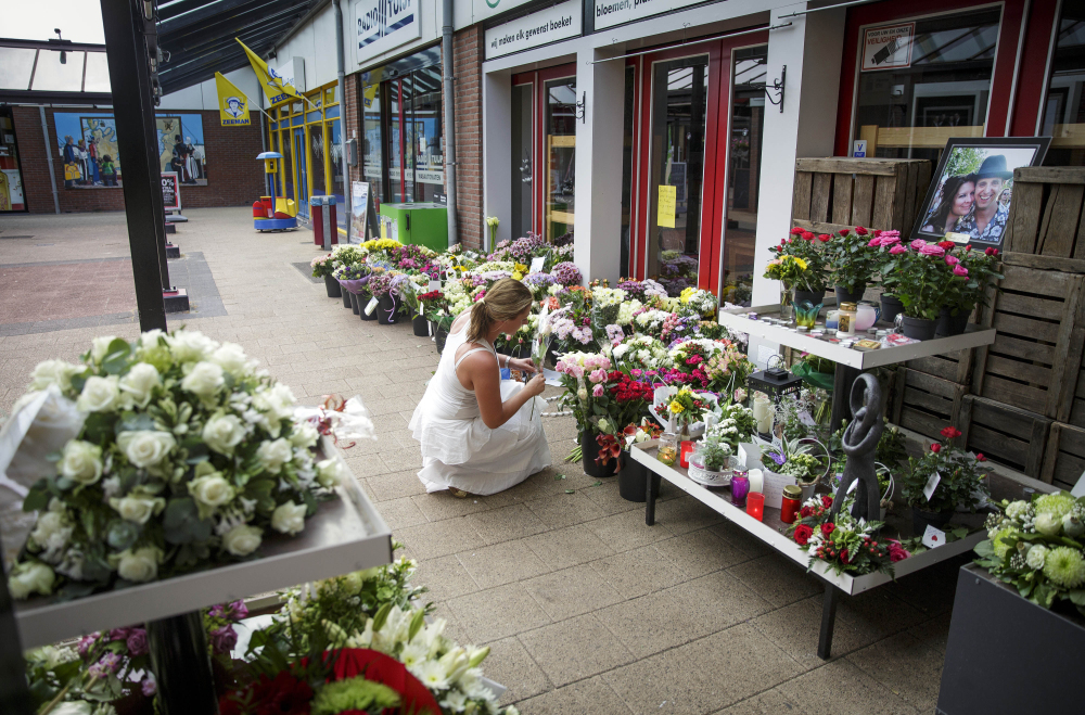 A portrait of Neeltje Tol, left, and Cor Schilder, right, is seen as a lady leaves flowers,  in front of their flower shop, in Volendam, Netherlands, Saturday.