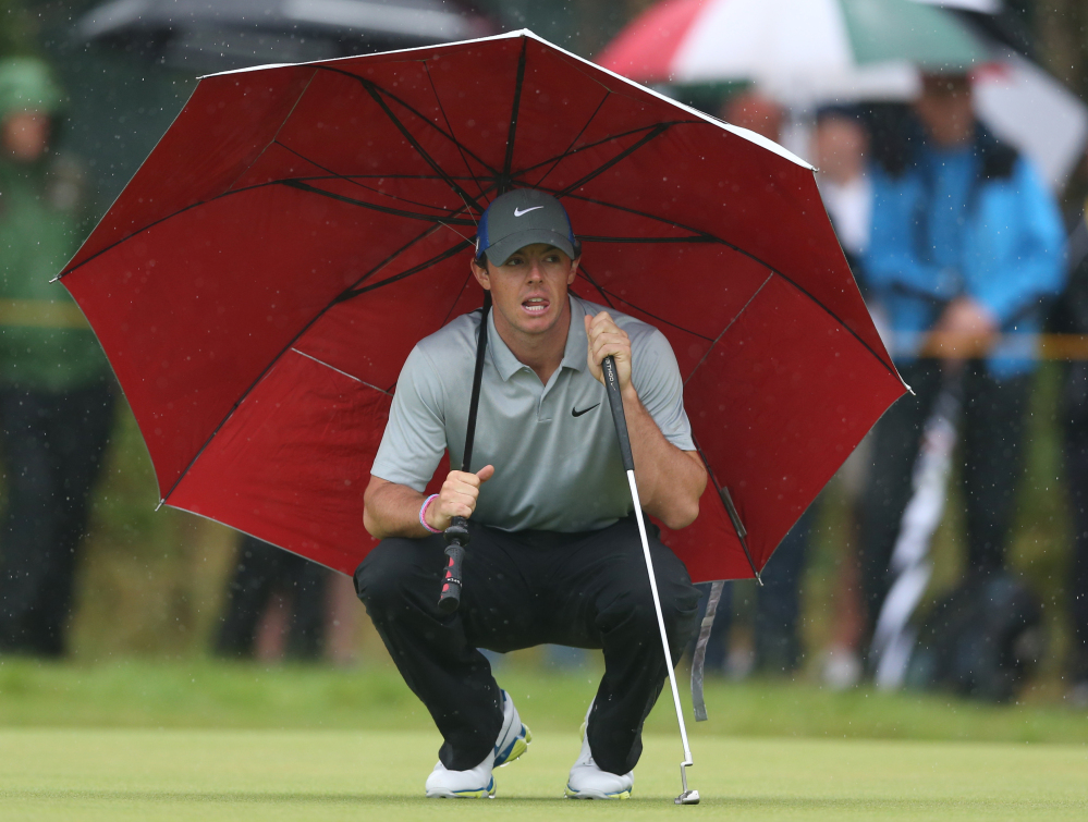 Rory McIlroy kneels under an umbrella as he waits to play on the 4th green Saturday during the third round of the British Open at the Royal Liverpool golf club.