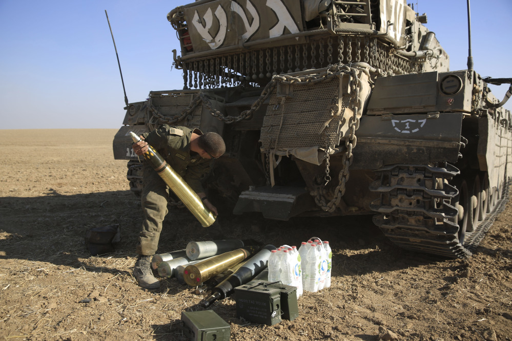 An Israeli soldier loads tank shells near the border of Israel and the Gaza Strip on Sunday. Escalating their ground offensive, Israeli troops backed by tanks and warplanes battled Hamas militants in a crowded neighborhood of Gaza City early Sunday.