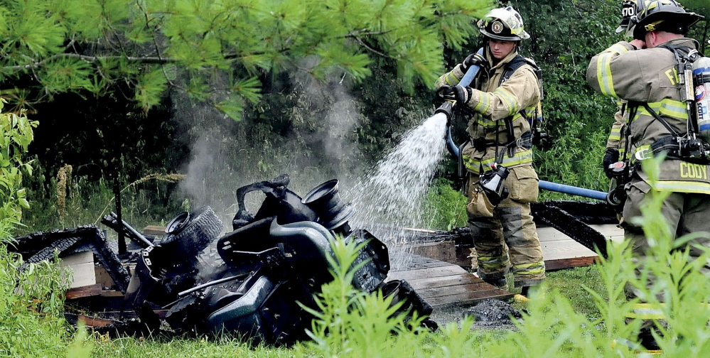 Fairfield firefighters spray water onto the smoldering remains of a lawnmower that burned Sunday after it was used and placed in a utility shed in Benton. The shed also caught fire.