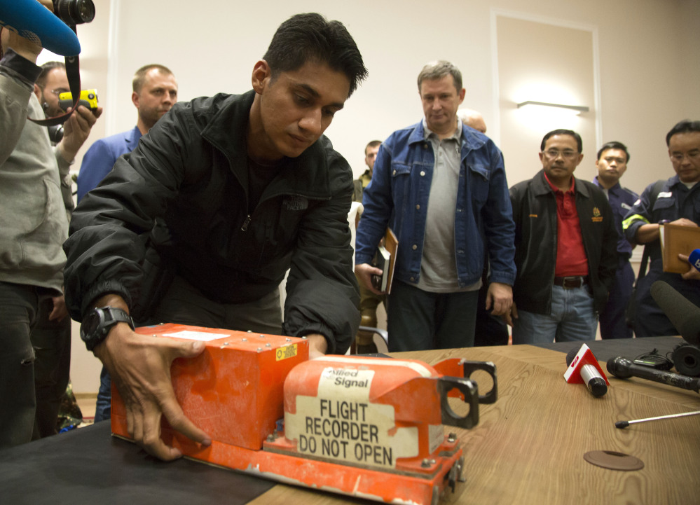A Malaysian investigator takes a black box from Malaysia Airlines Flight 17 as it is handed over from Donetsk People’s Republic officials to Malaysian representatives in the city of Donetsk, eastern Ukraine Tuesday.