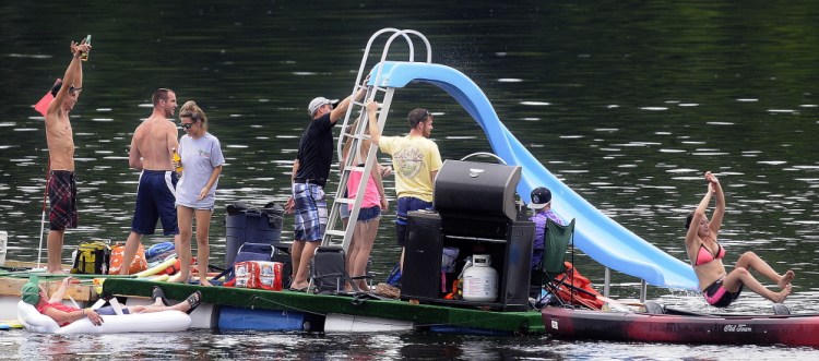 A raft on barrels carrying a water slide and a grill meanders down the Kennebec River on Sunday between Hallowell and Chelsea. More than 200 people showed up with inflated rafts, launched kayaks and drifted atop empty coolers during the second annual celebration of the river, which launched from Chelsea and Hallowell and came aground in Gardiner.