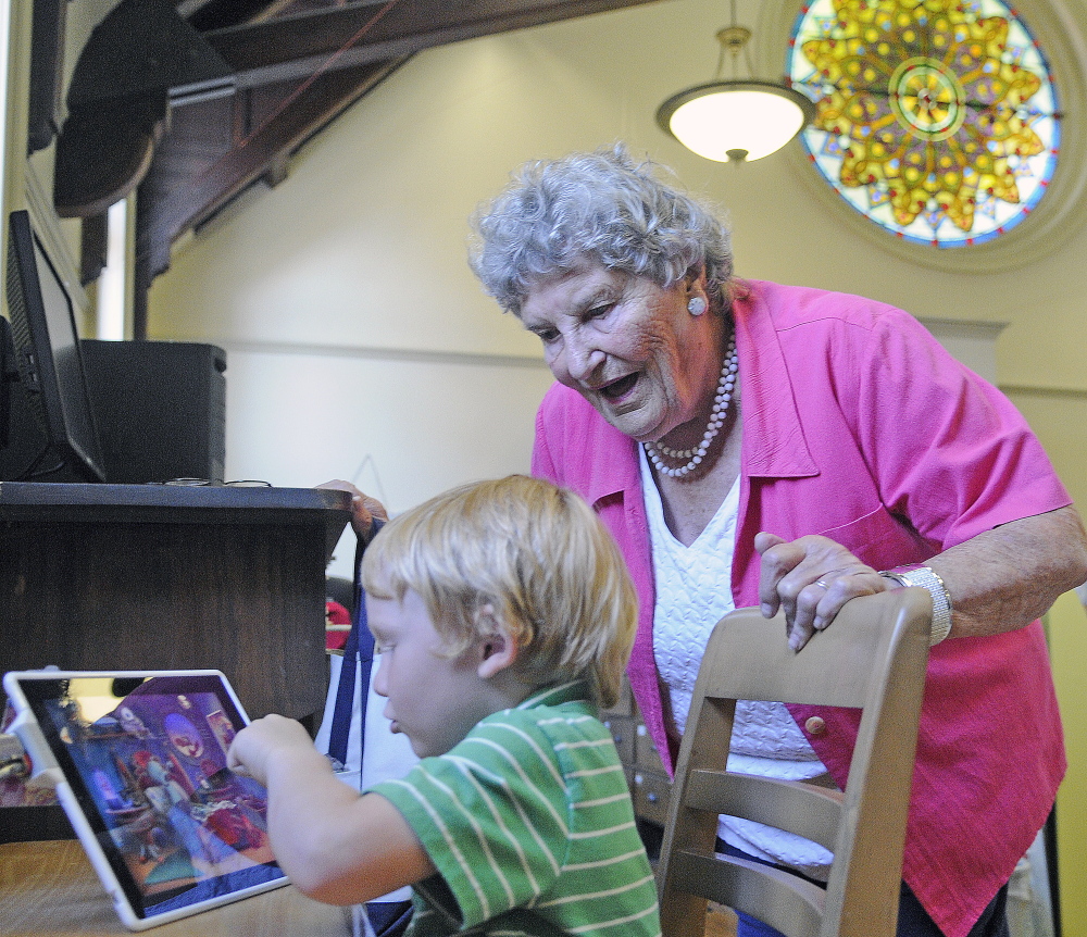 Randolph resident Shirley Hanley chats with Bimas Brown on Monday while he plays a game in the children’s reading room at the Gardiner Public Library. Hanley, who has been member of the library for 70 years, was selecting titles for her grandchildren.