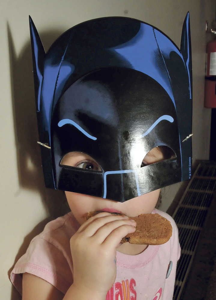 Even young Batgirls, like Natalie Ferris, get hungry. Natalie enjoyed the cookies during a celebration of the 75th anniversary of Batman at the Waterville Public Library.