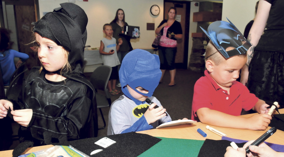 Kids turned out in costume at the Waterville Public Library Wednesday to celebrate the 75th anniversary of the creation of the Batman character. Kids and parents made decorations and watched a Batman movie. From left are Bianca and Bowen Wright and Judson Smith.