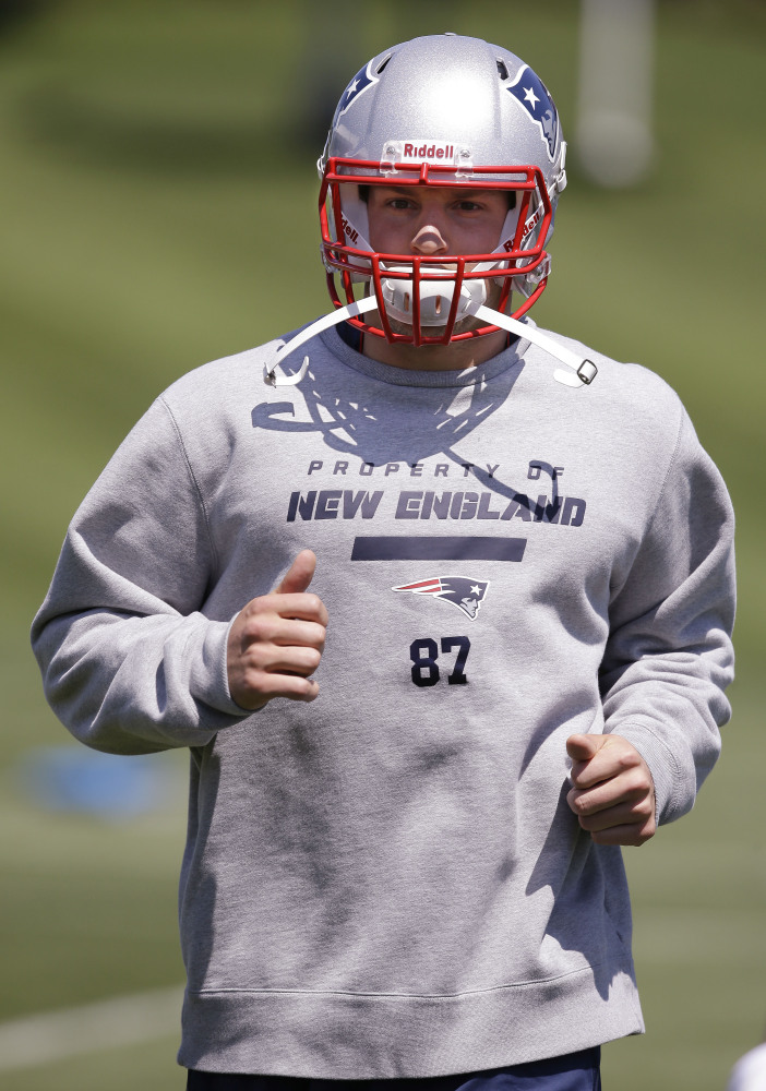 File-This May 30, 2014, file photo shows New England Patriots tight end Rob Gronkowski  running while stretching during an organized team activity at the NFL football team's facility  in Foxborough, Mass. When will Gronkowski play a full regular season? He missed five games in 2012 with a broken forearm and nine in 2013 while recovering from forearm and back surgery before tearing ligaments in his right knee. He participated on a limited basis in minicamp but ran hard on the sideline.  (AP Photo/Stephan Savoia, File)