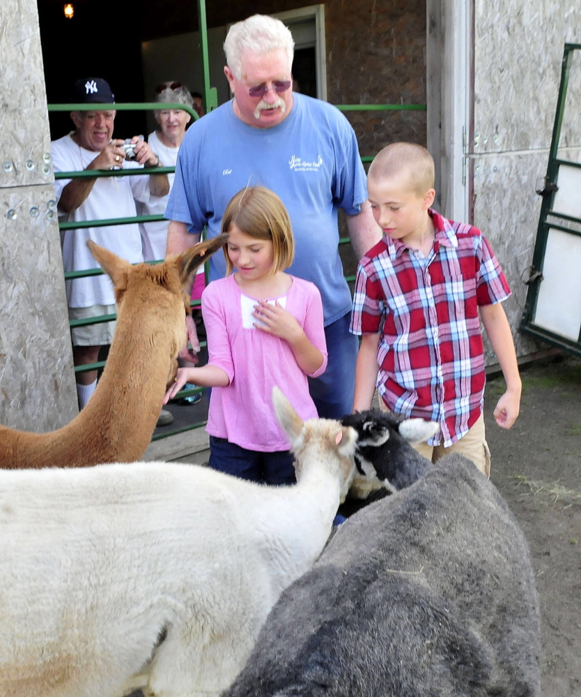 Misty Acres Alpaca Farm owner Red Laliberte watches as Madeline and Corbin Kissinger feed alpacas during the statewide Open Farm Day at the Sidney farm on Sunday, July 27, 2014.