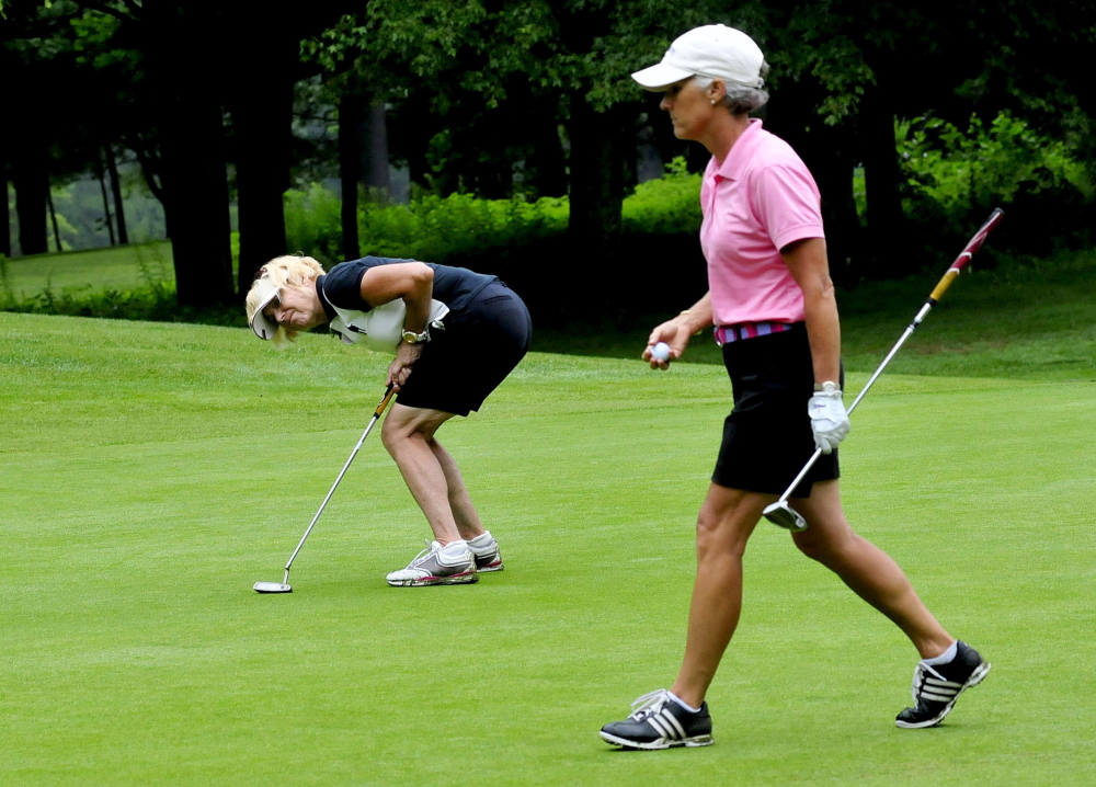 Debby Gardner, left, leans over hoping to coerce the ball she just hit roll closer to the hole during the Maine Women’s Amateur at the Waterville Country Club in Oakland on Monday.