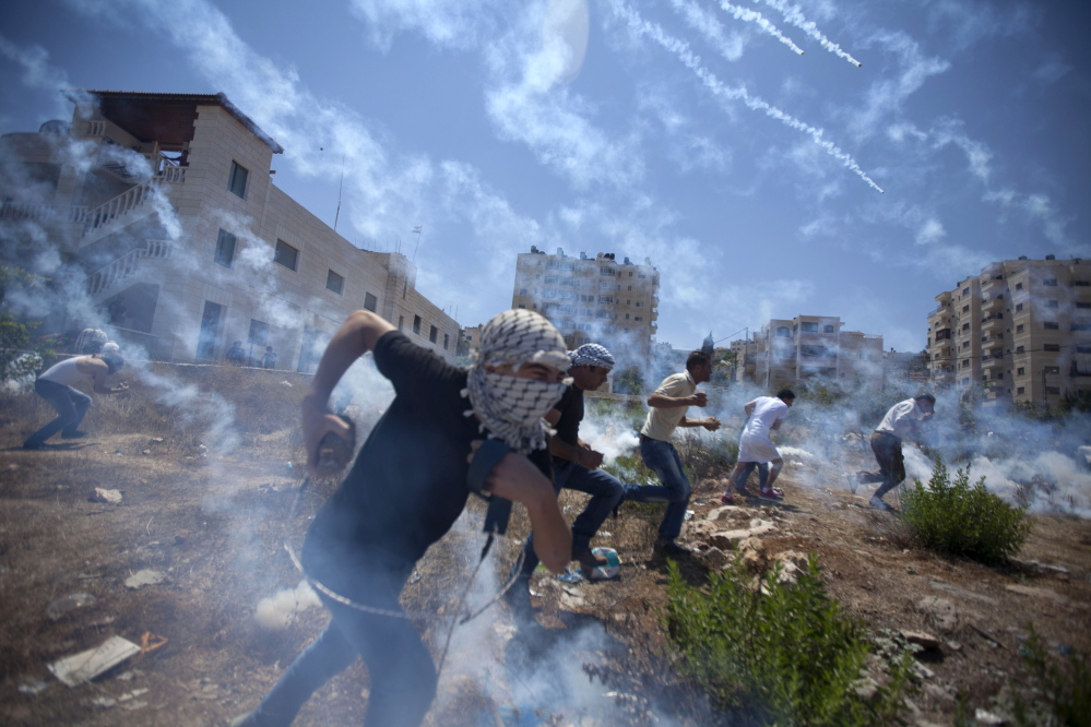 Palestinians run for cover during clashes with Israeli soldiers following a protest against the war in the Gaza Strip, outside Ofer, an Israeli military prison near the West Bank city of Ramallah, on Friday.