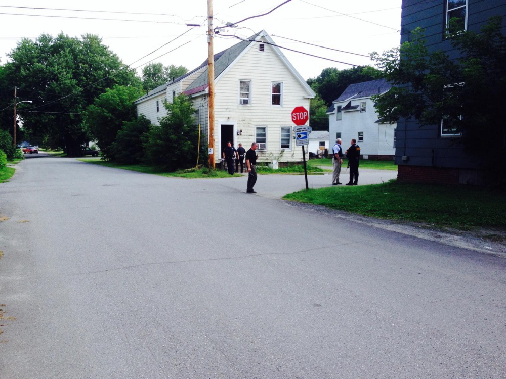 Police officers stand outside 25 Spruce St. in Waterville, where a man who threated to point a gun at point surrendered after a standoff lasting about 40 minutes.