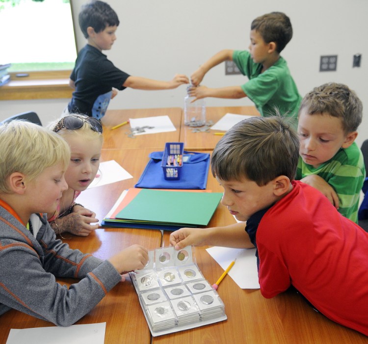 Augusta elementary school students examine a coin collection and count quarters last week at Cony High School while listening to Assistant Attorney General Steve Parker discuss economics.