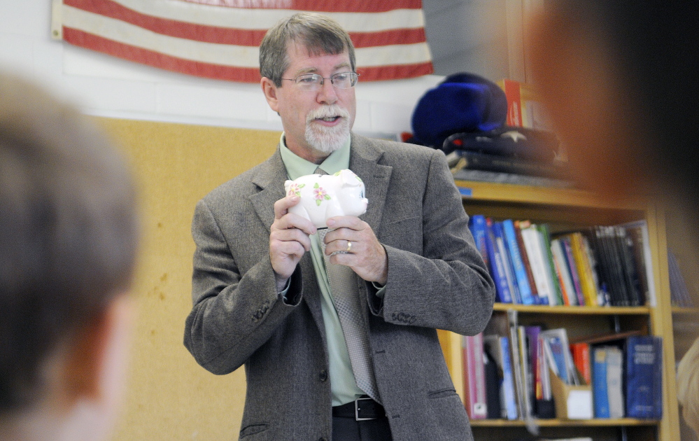 Assistant Attorney General Steve Parker clutches a piggy bank last week while speaking to Augusta elementary school students at Cony High School about the importance of understanding mathematics.