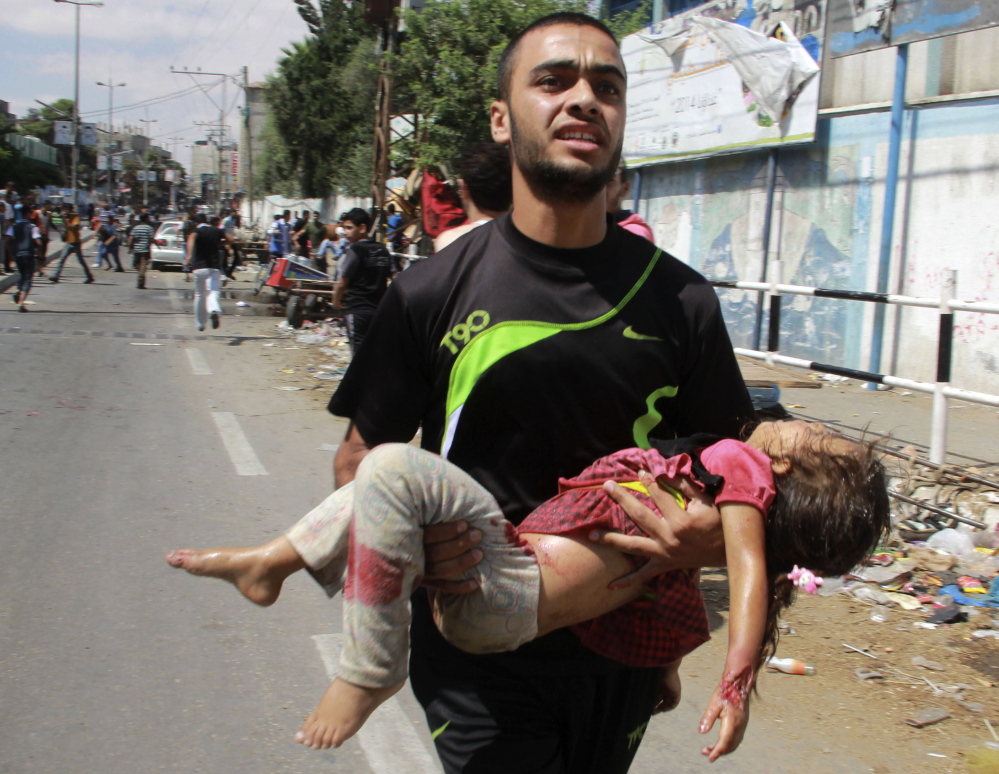 A Palestinian man carries a child killed in an apparent Israeli airstrike Sunday in the southern Gaza Strip near a U.N.-run school that was being used to provide shelter for about 3,000 people.