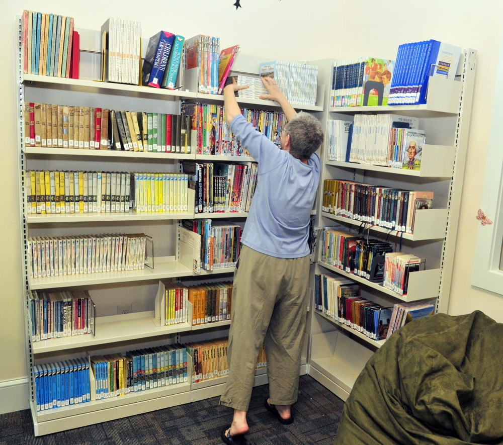 Board of trustees member Bonnie Dushin straightens books in the young adult area during a tour of new Umberhine Public Library on Thursday in Richmond.