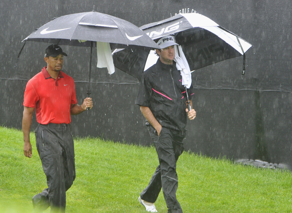 Tiger Woods, left, and Bubba Watson, walk off the course because of a rain delay at the first hole of the final round of the Bridgestone Invitational golf tournament, Sunday, in Akron, Ohio.