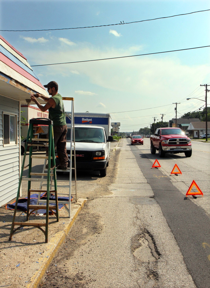 Martin Fernald prepares a former barber shop to be repainted as motorists drive up College Avenue in Waterville on Monday. College Avenue is one of several streets scheduled to be repaved.