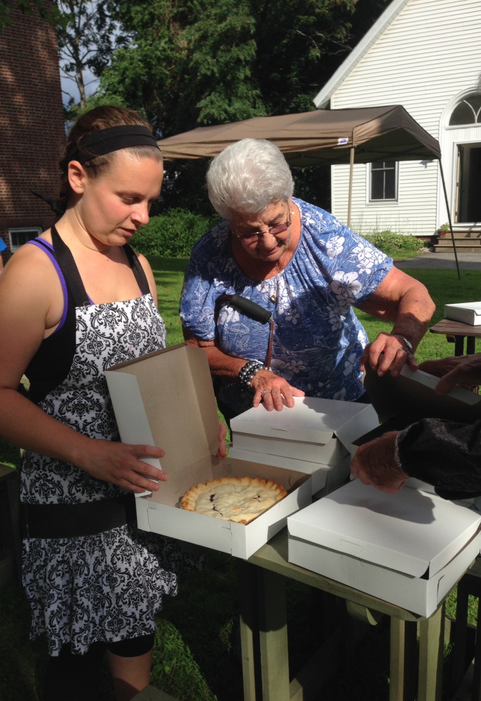 Normal (Web):Pauline Poulin, right inspects a table of blueberry pies staffed by Amy Fogg Friday night at Winslow Congregational Church. The church is hosting its 43rd annual Blueberry Festival on Saturday.