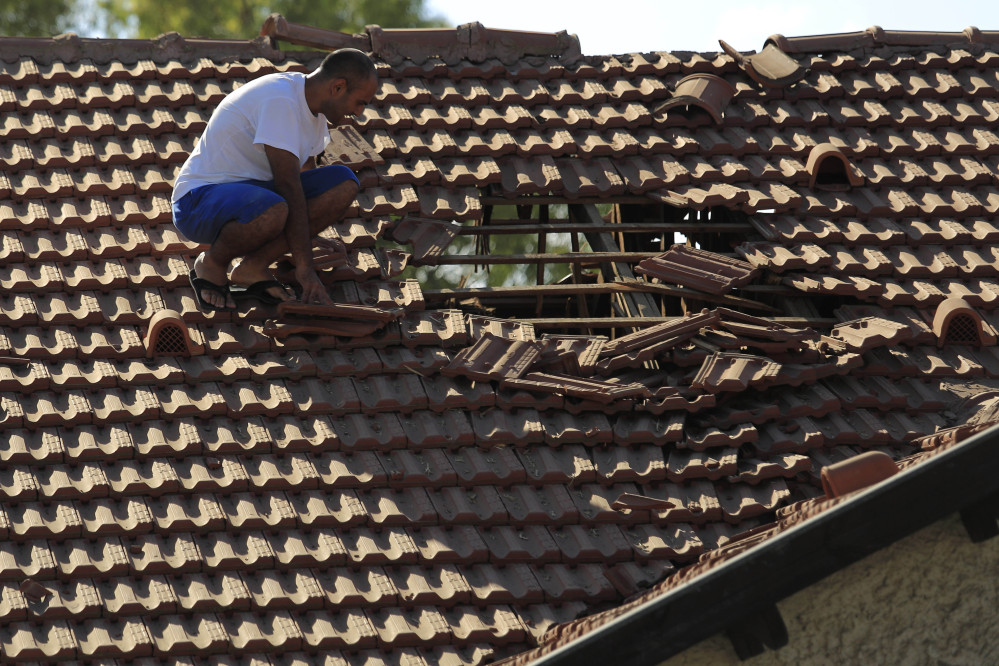 An Israeli man examines the damage to the roof of his house after a rocket fired from Gaza hit in a residential neighborhood of the southern city of Sderot, Israel, Friday.
