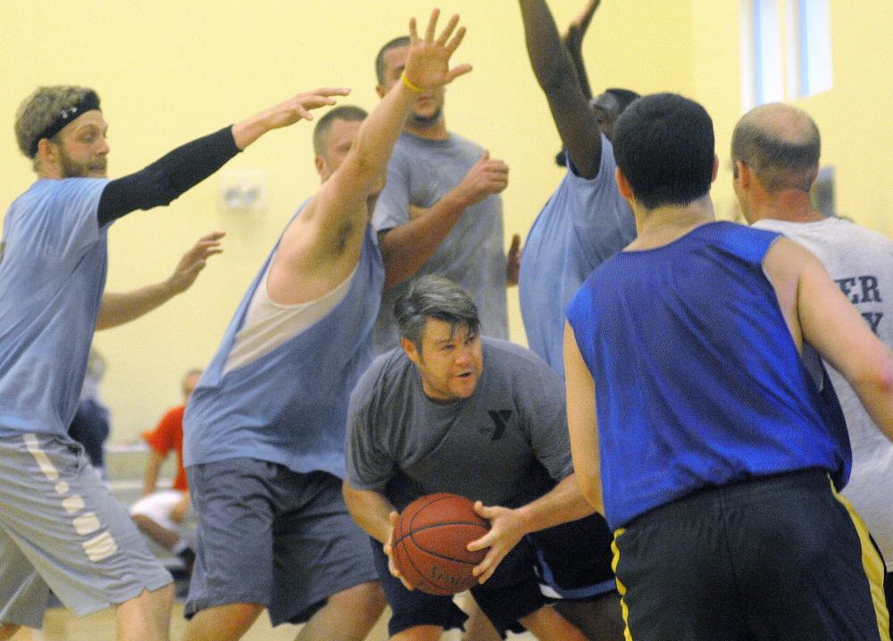 Nate Munzing is swarmed by defenders during a YMCA summer league basketball game Wednesday.
