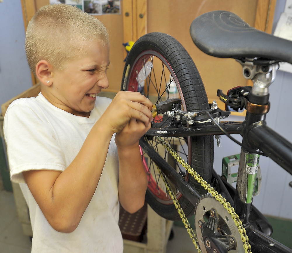 Ten-year-old Austin Cantara pulls hard on the wrench as he tightens a nut on the brake pad that he just replaced on his bike in the Community Bicycle Center, a non-profit agency in Biddeford. The agency prepares to leave its old site on Hill Street and move to a larger building a few blocks away.