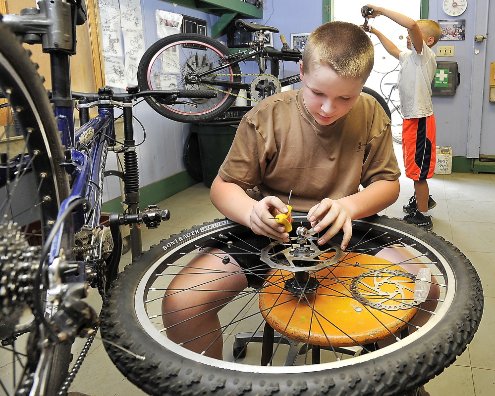 Cameron Roy, 13, works on a rear wheel at the Community Bicycle Center, a non-profit agency in Biddeford, that is preparing to leave its old site on Hill Street and move to a larger building several blocks away.