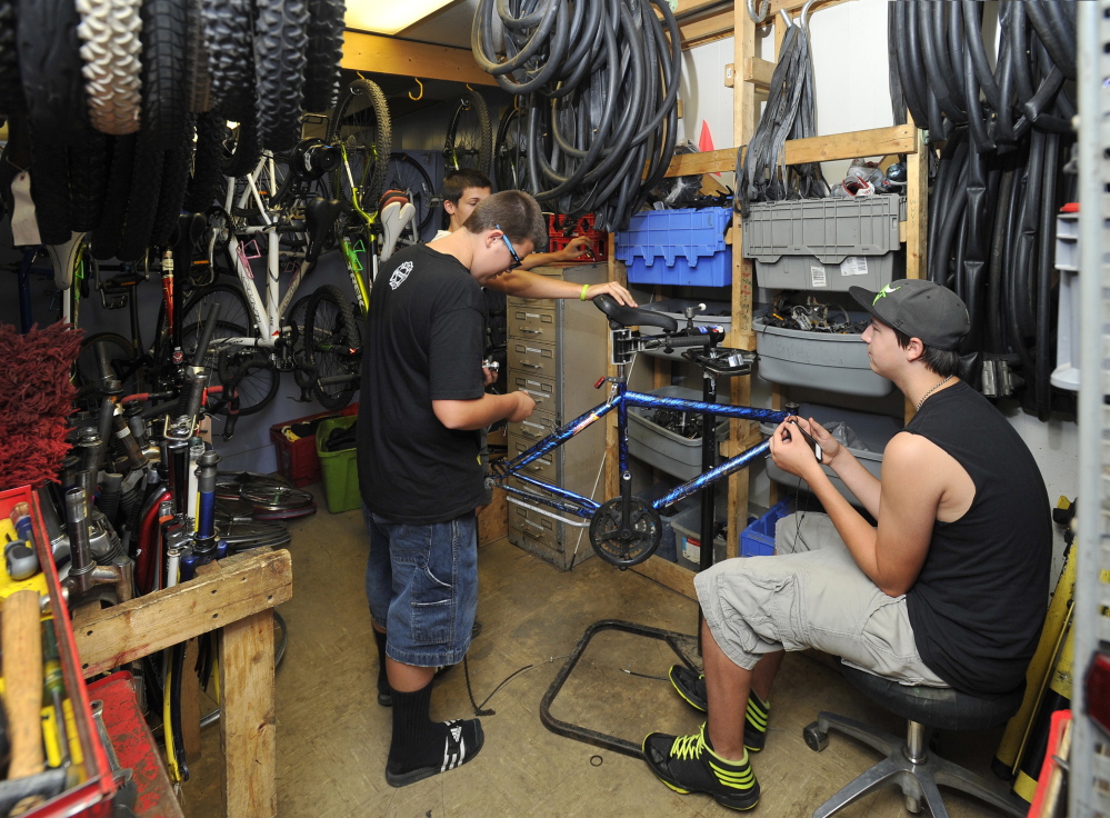 Three volunteers work in a cramped parts room refurbishing a bike at the Community Bicycle Center, a non-profit agency in Biddeford. The agency will leave its old site on Hill Street in September and move to a larger building several blocks away.