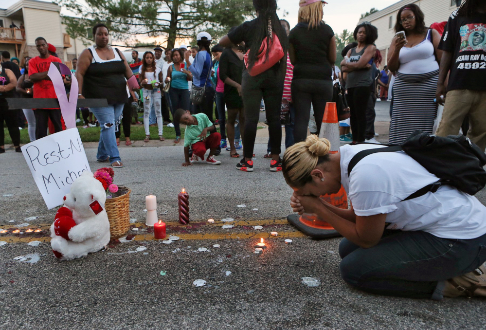 Meghan O’Donnell, 29, from St. Louis, prays at the spot where Michael Brown was killed, Sunday evening, in Ferguson, Mo.