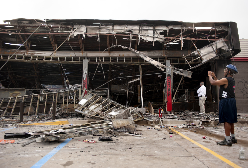Passers-by and media take a closer look Monday, at the burned-out shell of the QuikTrip gas station torched during the violence that erupted in Ferguson, Mo. overnight following a candle-light memorial for 18-year-old shooting victim Michael Brown.