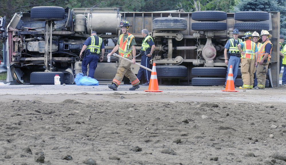 Police and firefighters converge Tuesday on an overturned dump truck on U.S. Route 202 in Winthrop.  The operator pulled over, according to police, to yield to an ambulance when he lost control.  The driver suffered bumps and bruises, state police said, but did not wish to be transported to a hospital. Traffic was reduced to one lane on the road as crews prepared to right the truck.